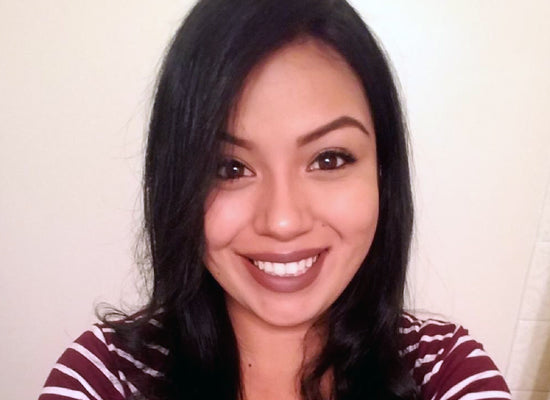 Woman with long dark hair wearing a striped shirt against a plain background