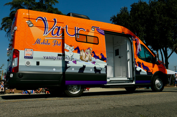 Orange van with 'Vanity Mobile Pet' branding on a street.